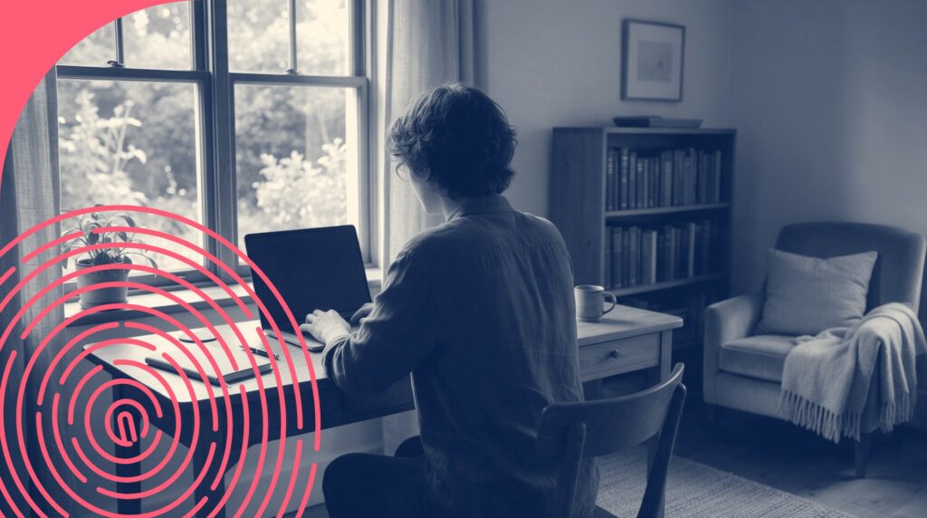 Personne vue de dos à un bureau à domicile qui utilise un ordinateur portable, avec carnet, plante et tasse
